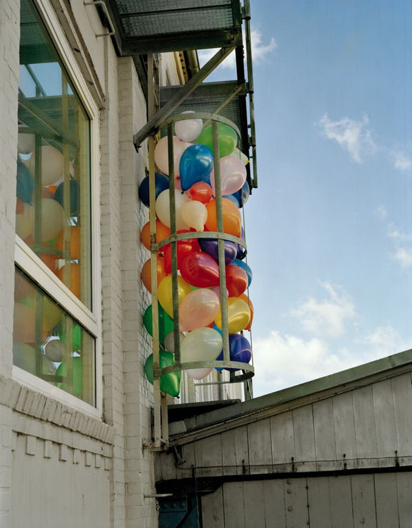 A colourful image of balloons alongside a building, by Polish artist Oliver Schwarzwald.